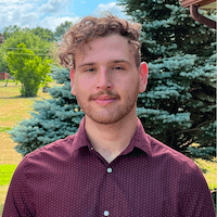 A picture of Khalil Nayef smiling in front of a tree with a blue sky in the background